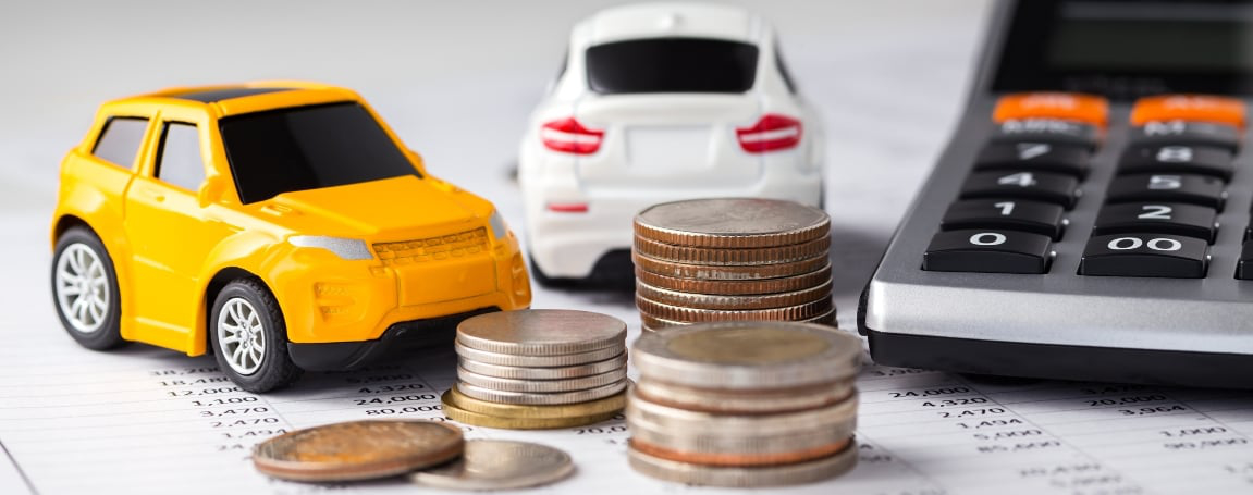 petites auto jouets a côté de piles de monnaie, factures et calculatrie