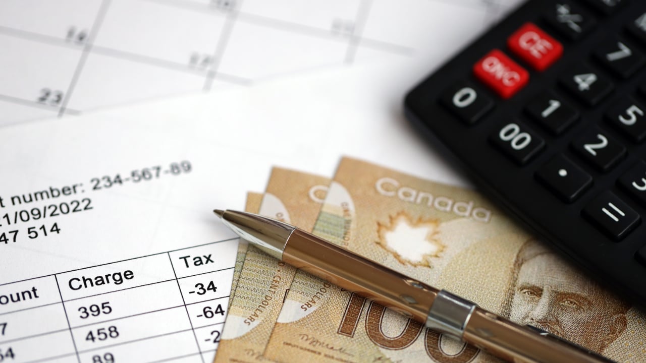 argent canadien sur une pile de papiers à côté d'une calculatrice