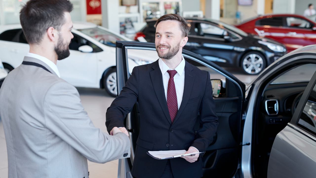 man shaking the hand of a car dealership sales person