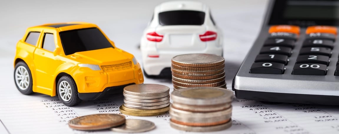 toy car next to a calculator and piles of coins