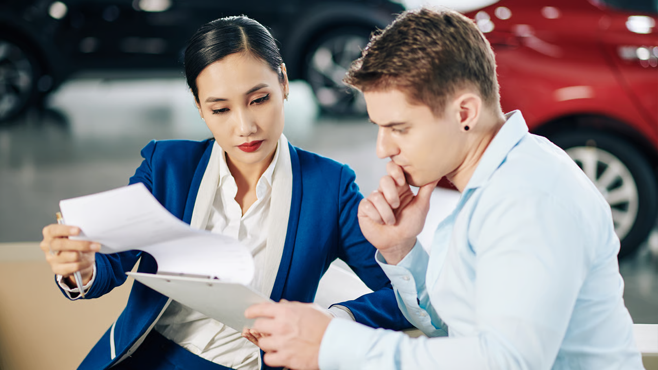 Jeune homme obtenant un financement auto et lis le contrat d'achat de la voiture