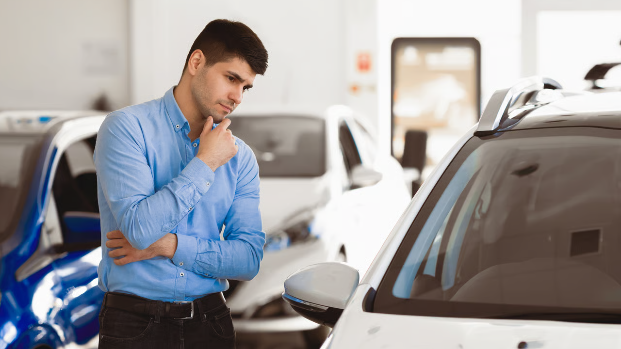 Vue d'un homme au concessionaire réfléchissant sur le financement de sa nouvelle voiture