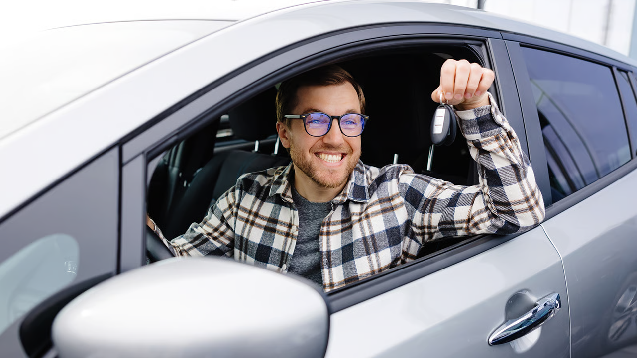 Homme à lunettes travailleur autonome excité de sa nouvelle voiture