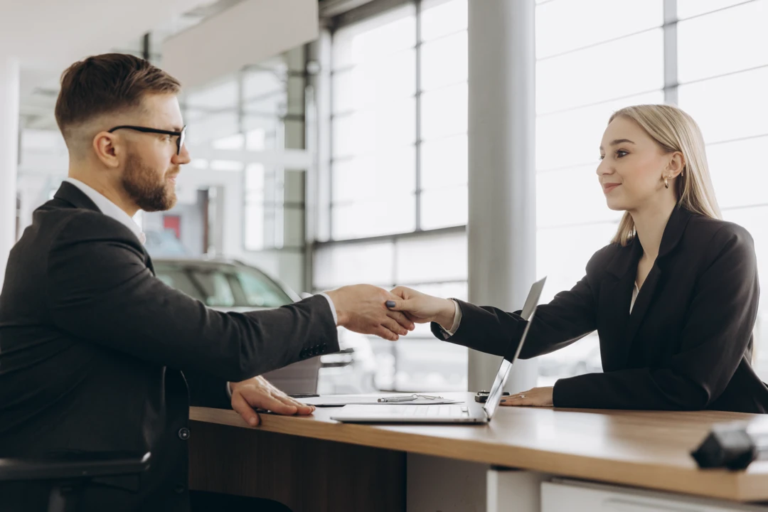 Customer and financial advisor shaking hands during a discussion about auto financing.