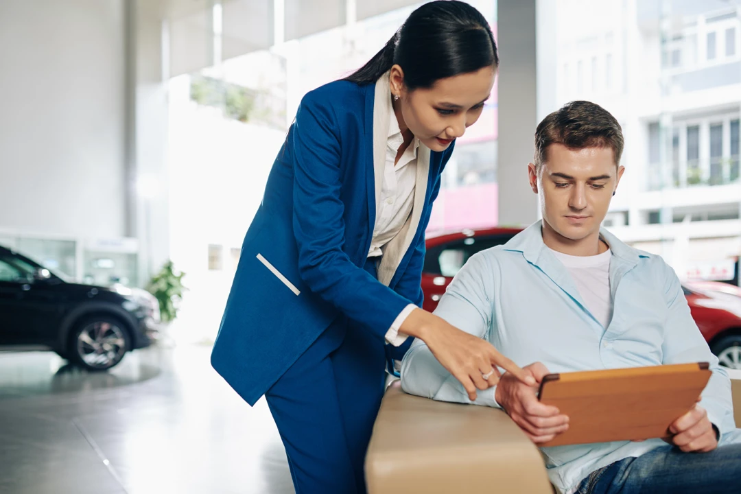 Advisor and customer reviewing an auto financing application on a tablet.