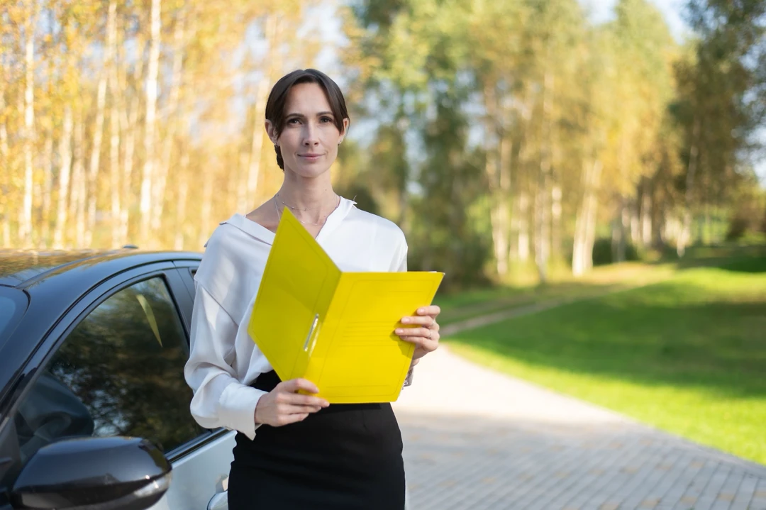 Woman reviewing financial documents beside a car, illustrating the assessment of late payments.