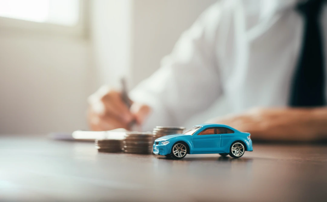 Person preparing documents beside coins and a miniature car, illustrating second-chance auto financing.