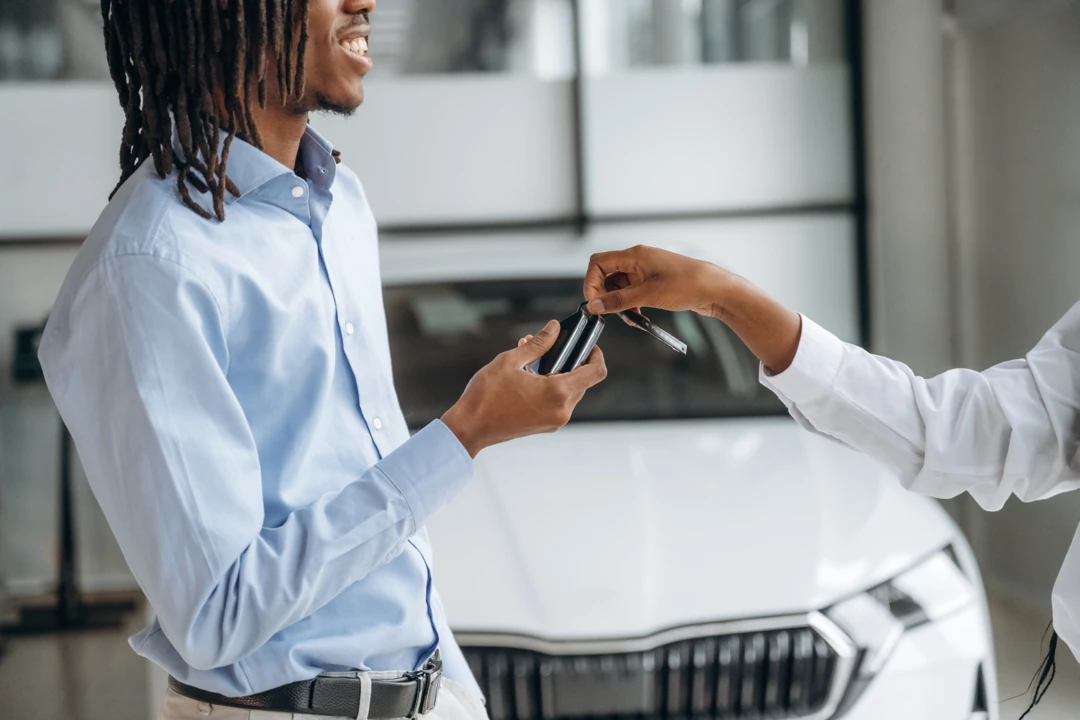 Customer receiving a car key, illustrating vehicle financing after reducing debt or lowering the financed amount.