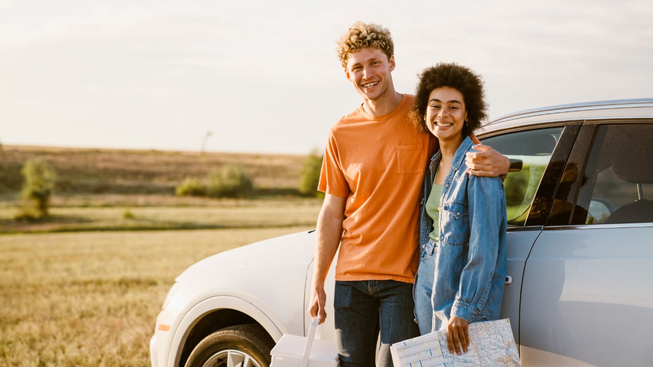 jeune couple devant leur auto dan un champ