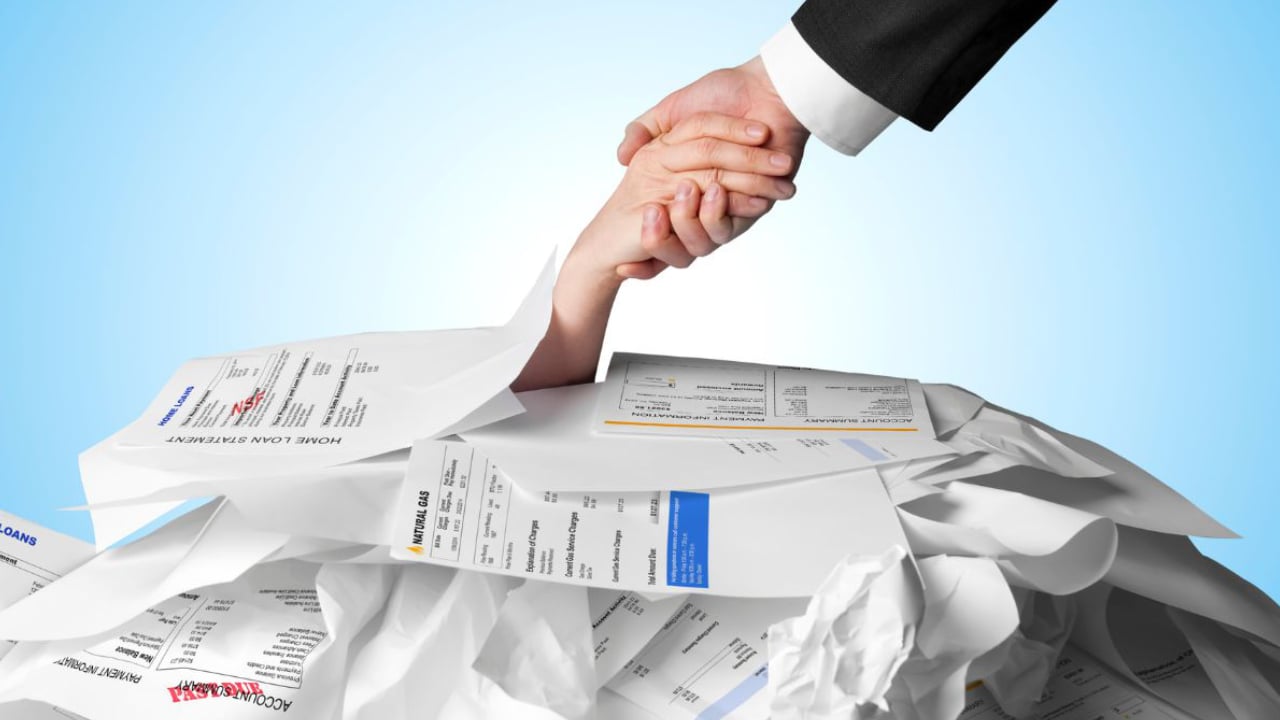 quelqu'un qui prend la main d'une personne prise sous une montagne de factures