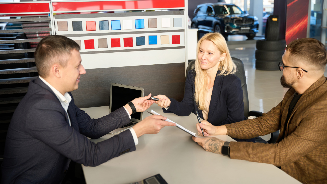 couple en train de récupérer la clé de leur nouveau véhicule dans un concessionnaire