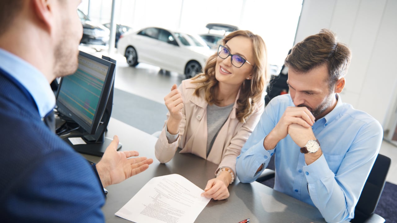 couple en train de discuter avec un représentant dans un concessionnaire