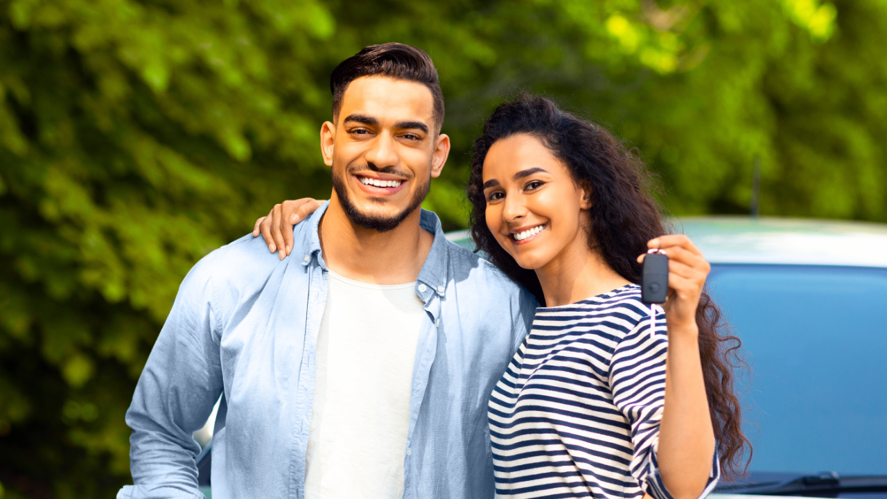 jeune couple qui présente la clé de leur nouveau véhicule