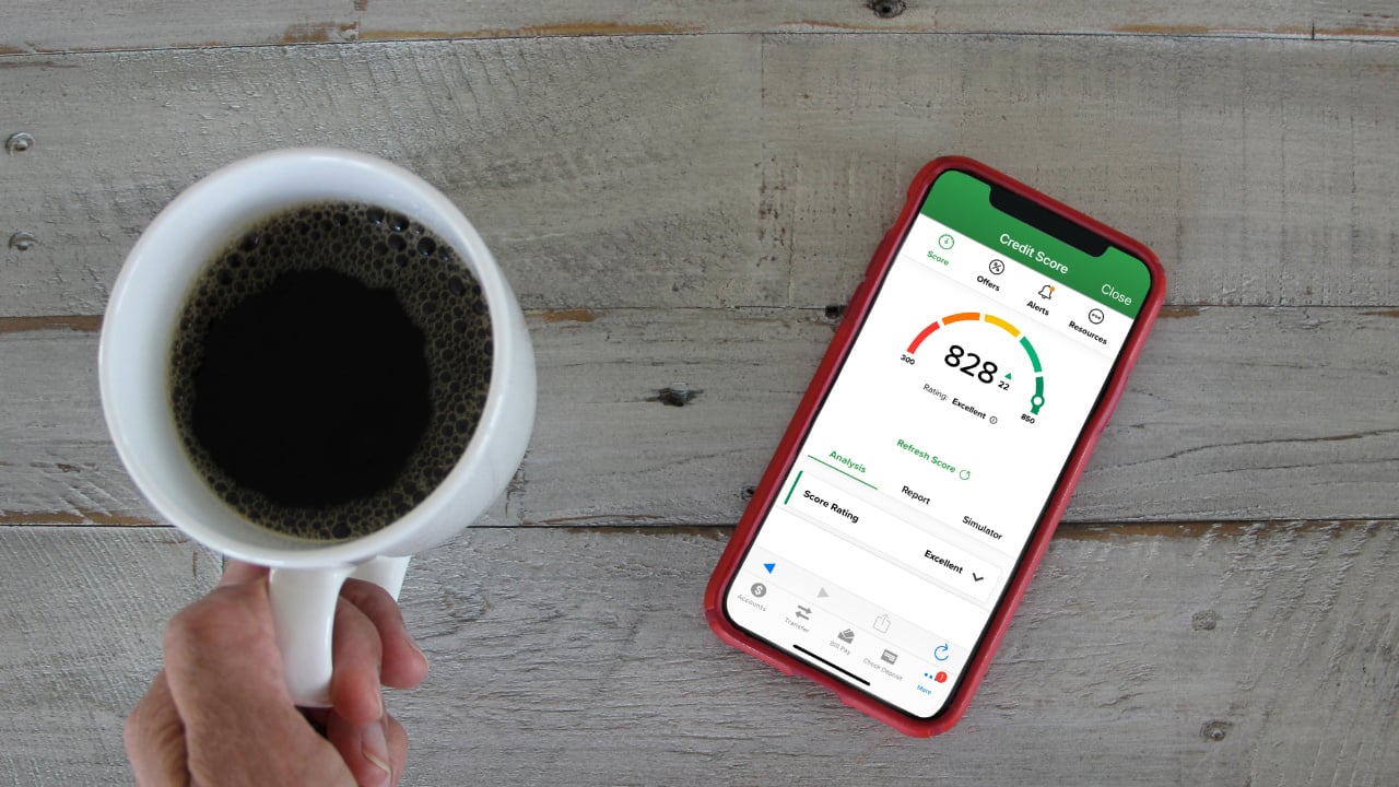 person checking on their credit score on their phone while drinking a coffee
