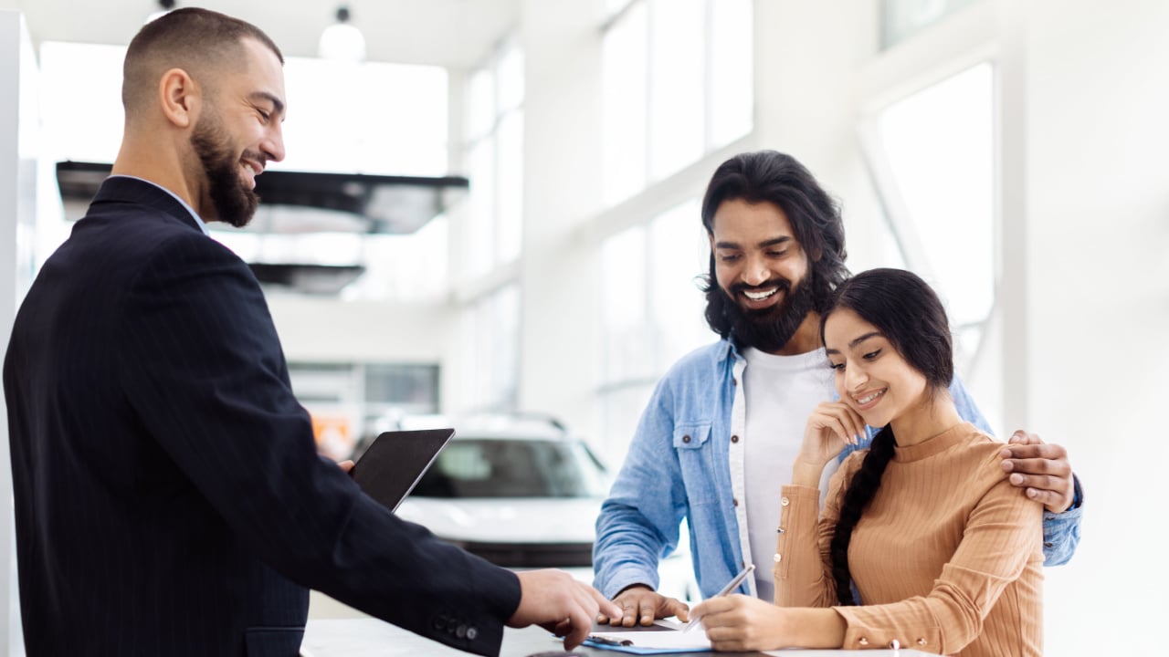 couple signing papers in a car dealership