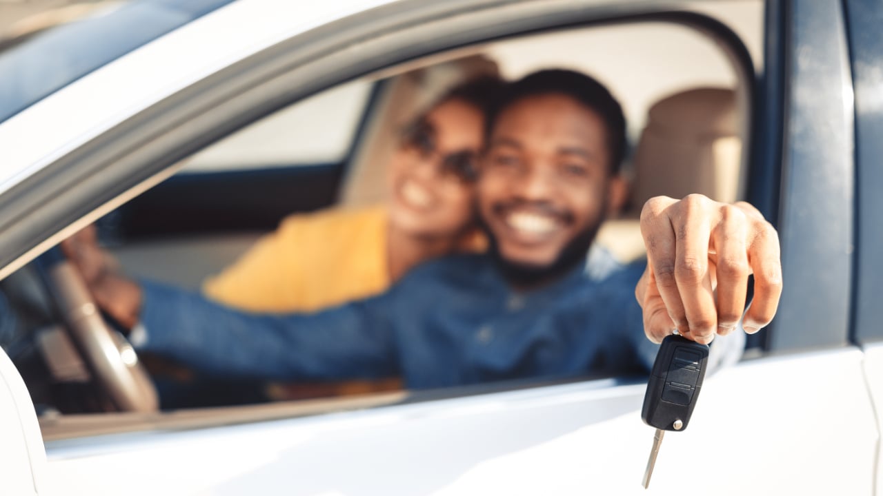 couple in a new vehicle with a man showing his car keys