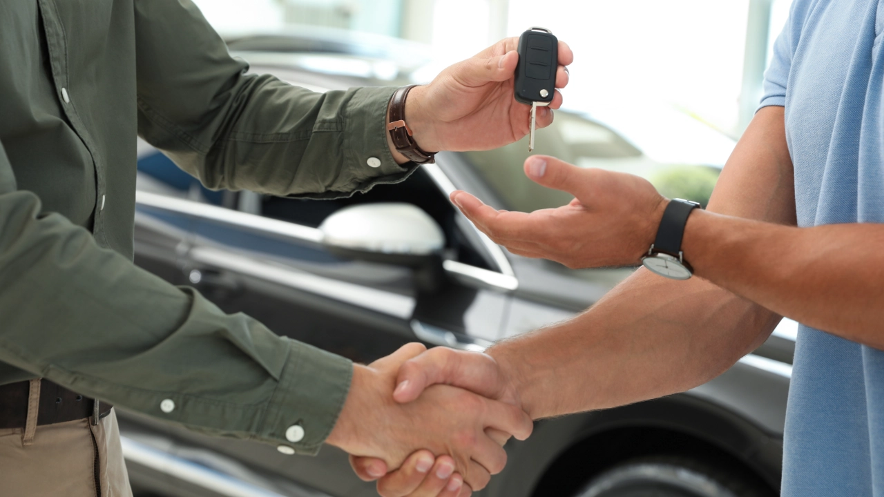 man shaking the hand of sales representative while receiving his keys