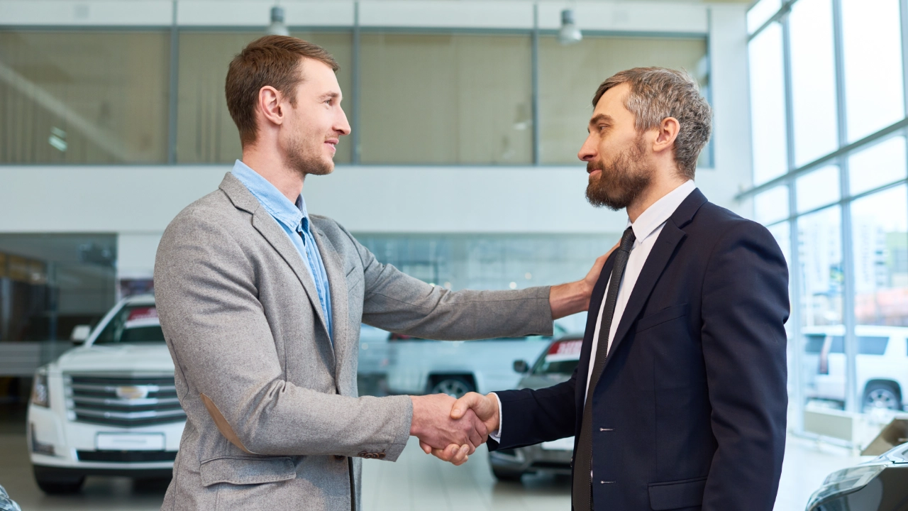 man shaking the hand of sales representative at a dealership