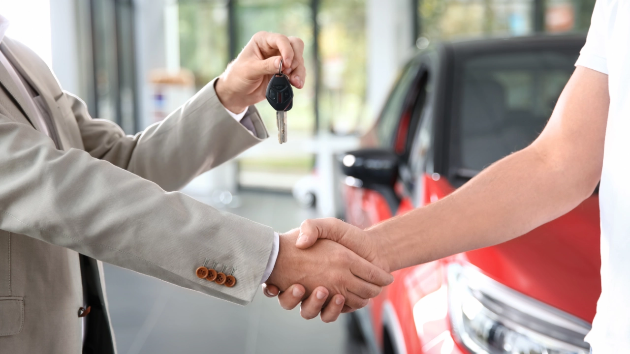 man shaking the hand of sales representative while receiving his keys