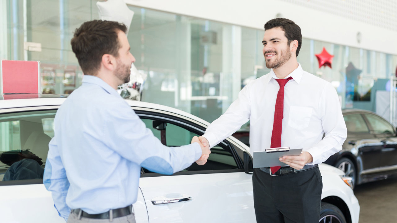 man shaking the hand of sales representative at a dealership