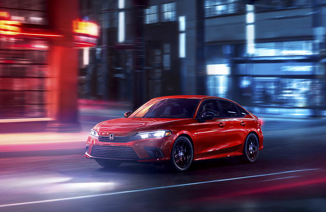 vue trois quart avant de la Honda Civic berline Sport 2022 roulant sur une rue urbaine
